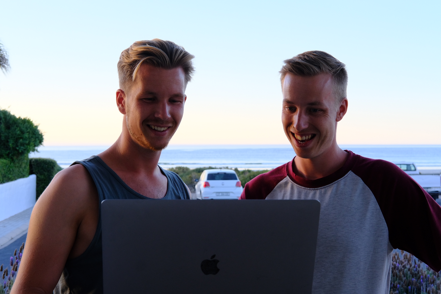 Unsere Gründer Simon und Michael stehen vor dem Laptop im Freien und lachen
