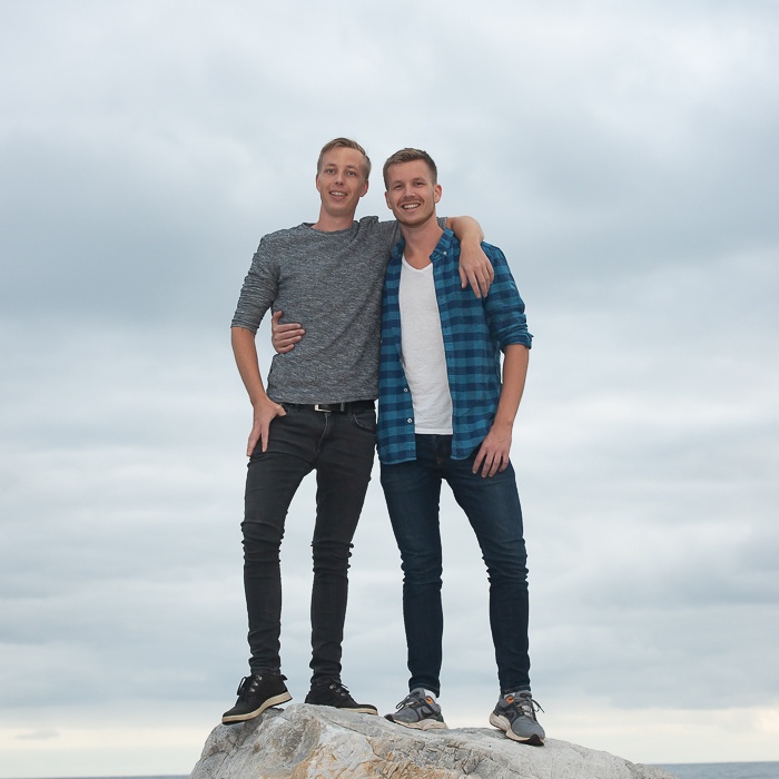 Zwei Gründer Arm in Arm auf einem Fels am Meer